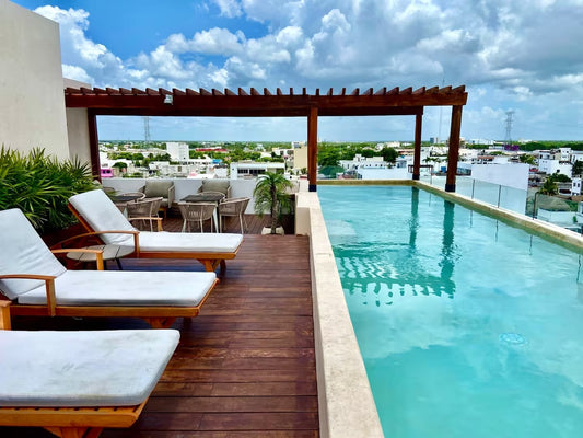 una alberca con un pergolado y camastros en tzalam residences playa del carmen