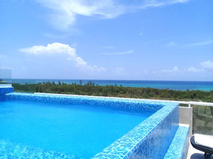 una alberca con camastros y vista al mar en bianco playa del carmen