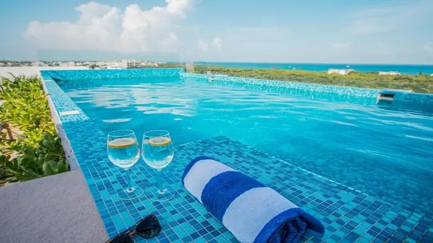 una alberca con unas copas de vino en condo xifra playa del carmen