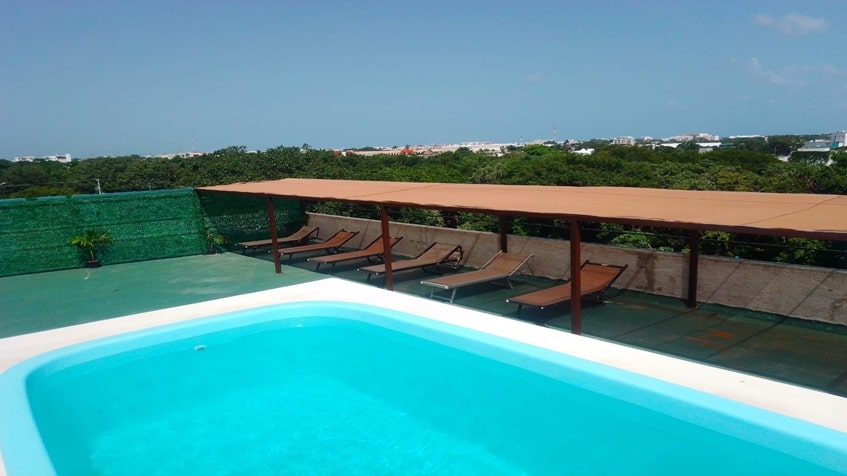 una alberca con camastros y vista a la ciudad en edificio ejidal playa del carmen