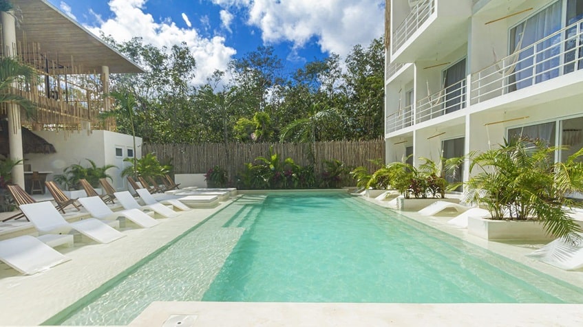 una alberca con plantas alrededor y area de solarium en muuk tulum