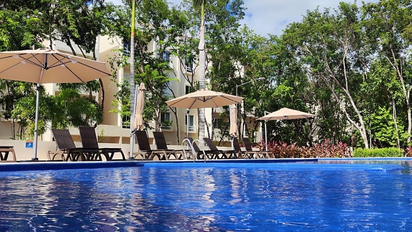 una alberca con camastros y sombrillas en la selva residences playa del carmen