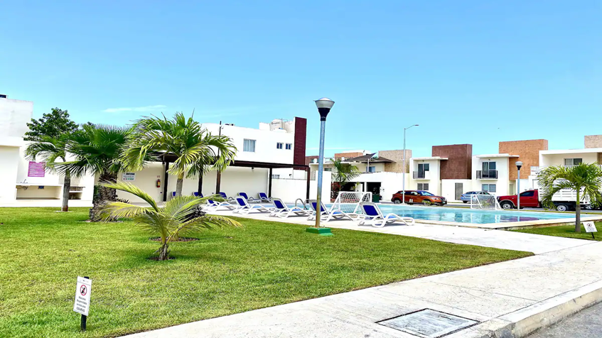 un jardin y una alberca con camastros en real del sol playa del carmen