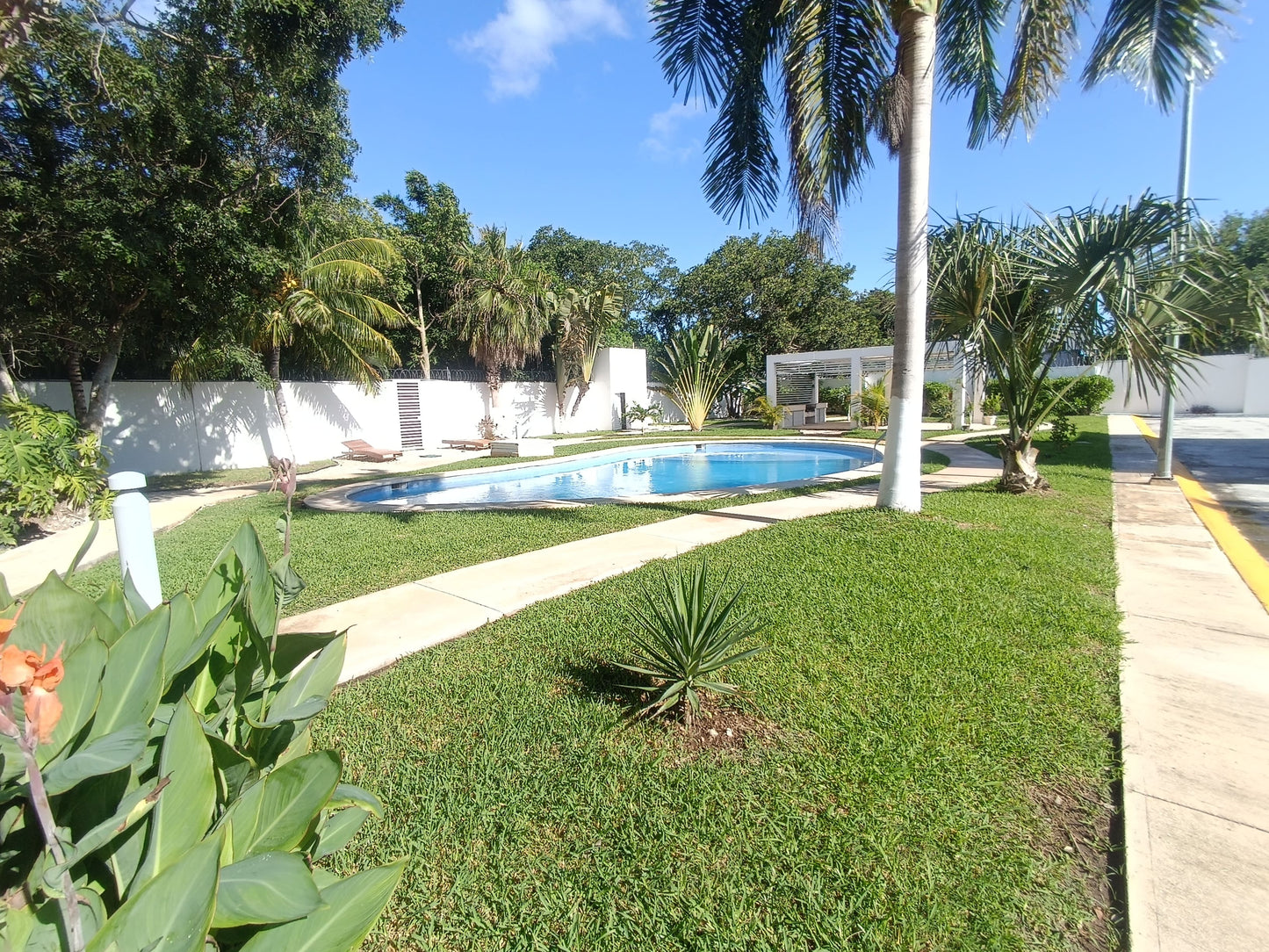 una alberca con grandes areas verdes alrededor en residencial lunamar playa del carmen