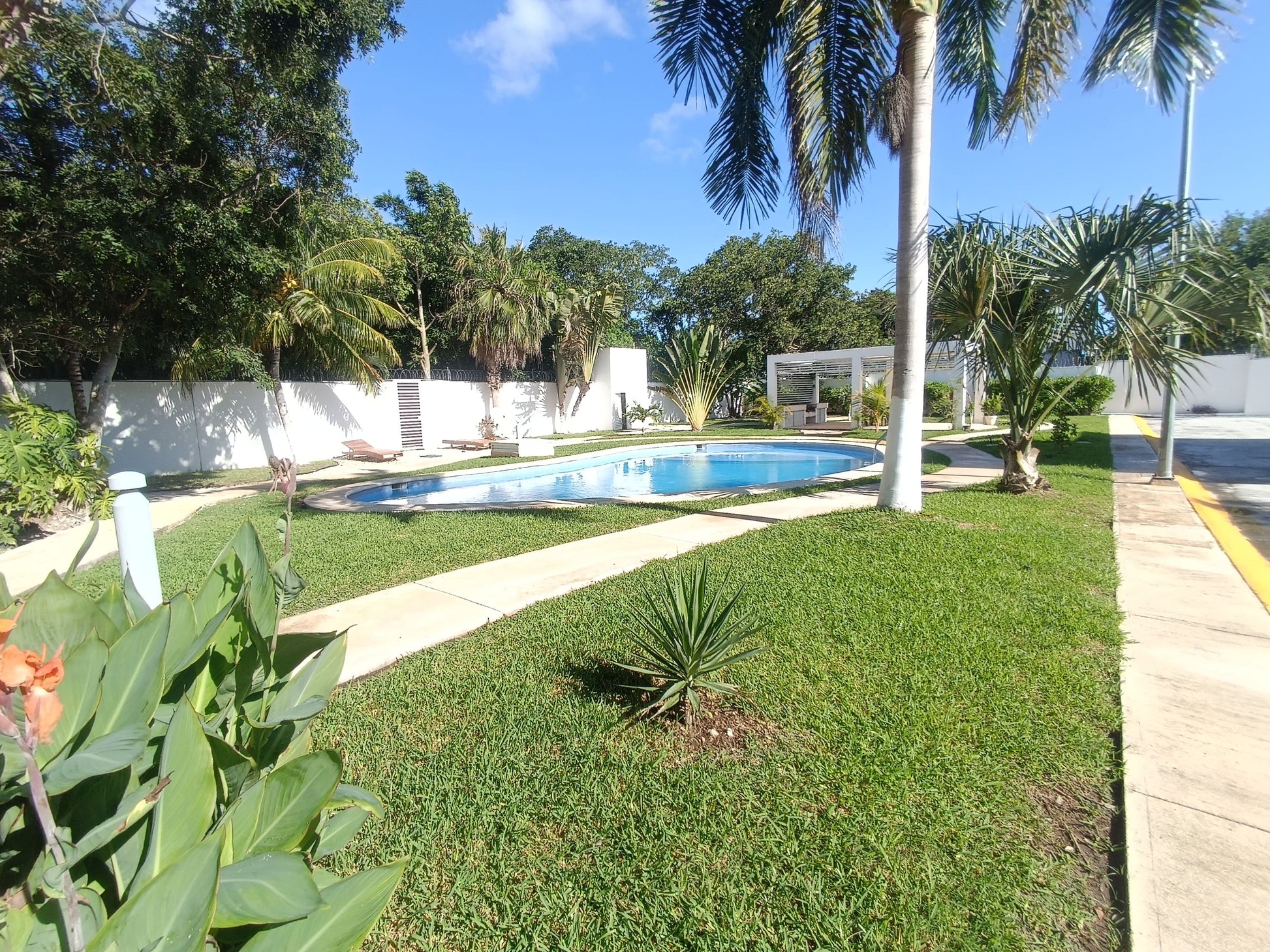 una alberca con grandes areas verdes alrededor en residencial lunamar playa del carmen