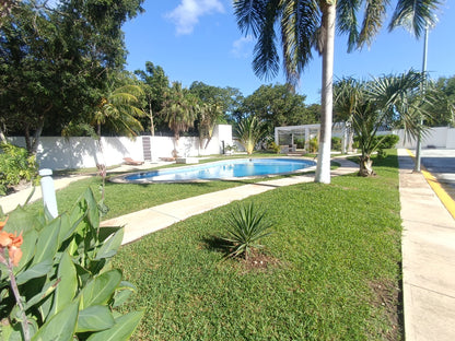 una alberca con grandes areas verdes alrededor en residencial lunamar playa del carmen
