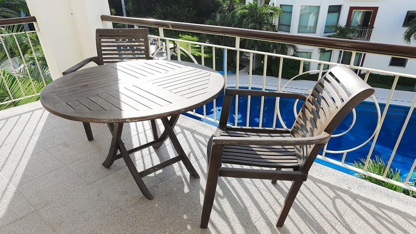 un balcon con 1 mesa y 2 sillas con vista a la alberca en paseo del sol playacar