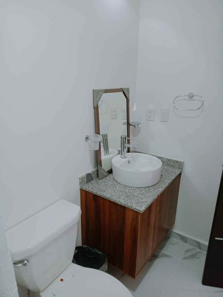 un baño con un lavamanos, un espejo y un excusado en la selva residences playa del carmen