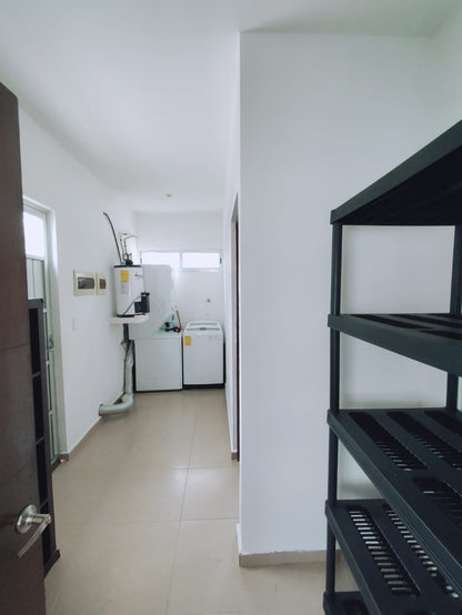 un centro de lavado con una lavadora y un rack para poner cosas en residencial playa magna playa del carmen