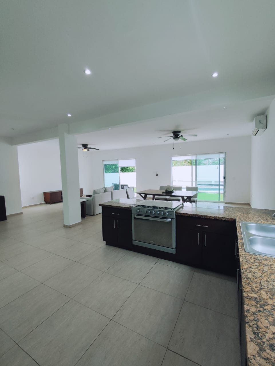 una cocina con una estufa, una sala, un ventilador y un aire acondicionado en residencial playa magna playa del carmen