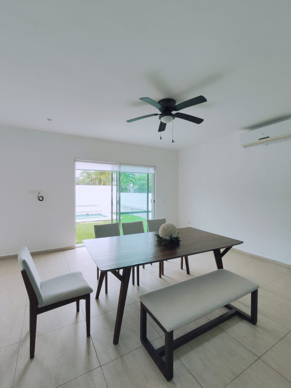 un comedor de madera grande con vista al jardin y a la alberca en residencial playa magna playa del carmen