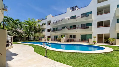 una fachada exterior de un edificio con departamentos y una alberca en condo margaritas playa del carmen