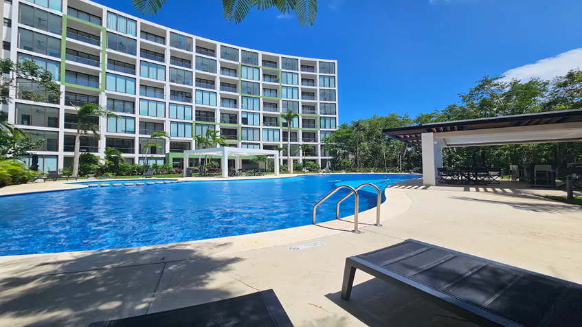 una fachada de un edificio de departamentos y una alberca en la ceiba mayakoba playa del carmen