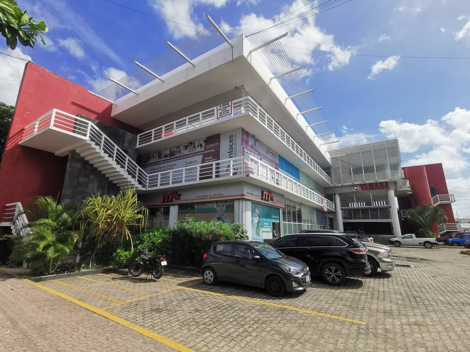 una fachada de un edificio con estacionamiento grande en plaza yamaha playa del carmen