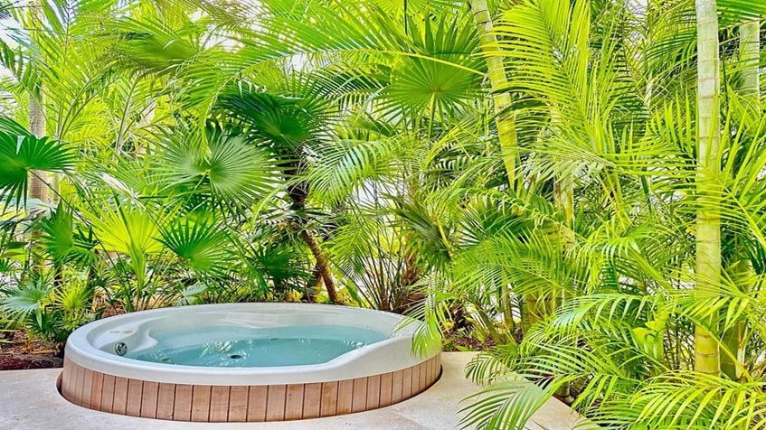 un jacuzzi con areas verdes en anah condos playa del carmen