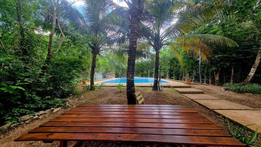 una mesa de madera con vista a la alberca en selvanova coto 2b playa del carmen
