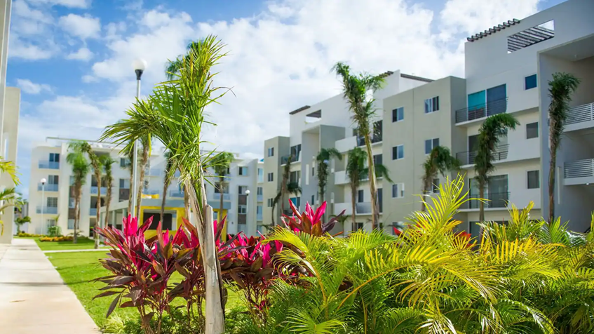 una fachada de departamentos y areas verdes  en paseo los olivos playa del carmen