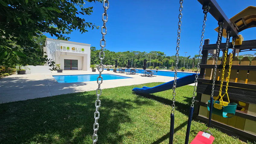 un parque infantil con juegos y alberca en la ceiba mayakoba playa del carmen