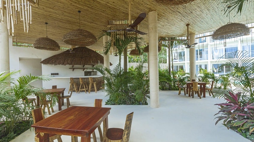 una entrada a un area de un bar con mesas y sillas en muuk tulum