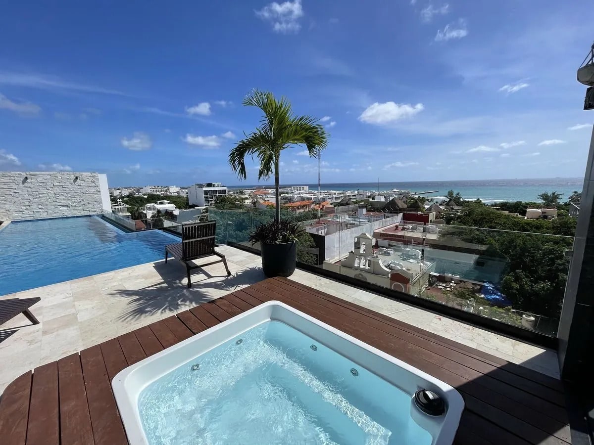 una piscina y un jacuzzi con vista al mar en a perfect place playa del carmen