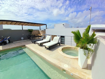 una piscina, un jacuzzi y un area de camastros en menesse on the beach playa del carmen
