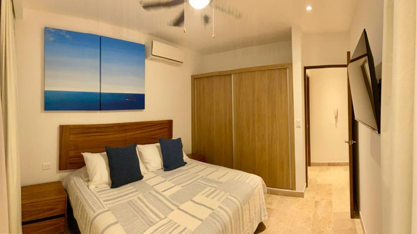 una recamara con una cama queen size, un cuadro decorativo y closets en ipana condos playa del carmen