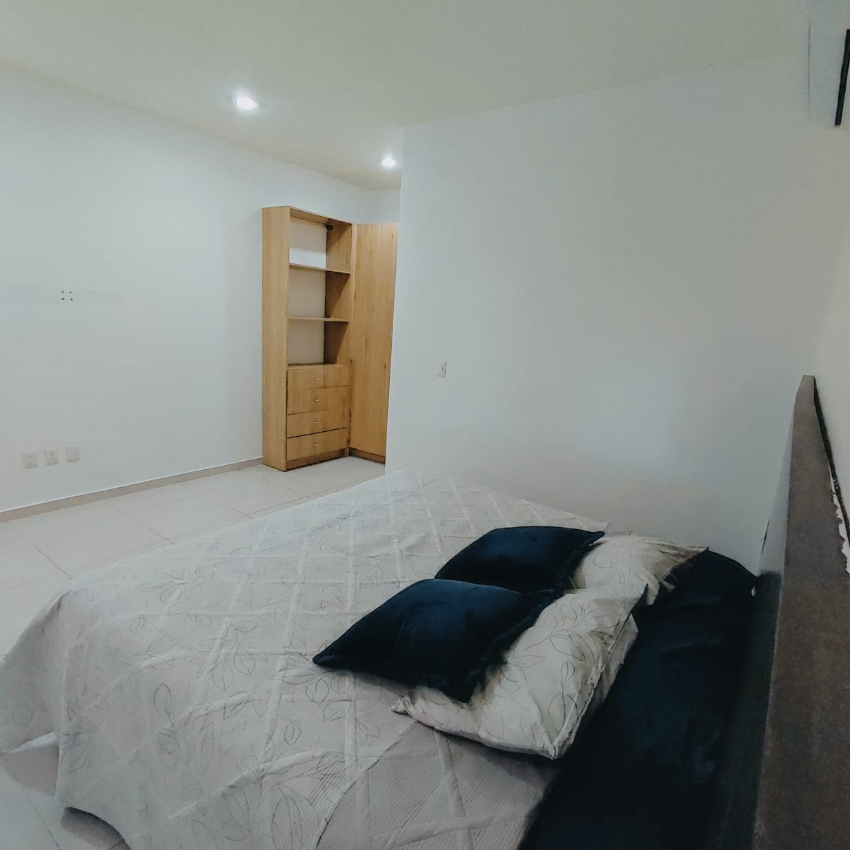 una recamara con una cama king size y un closet de madera en playa aurora playa del carmen
