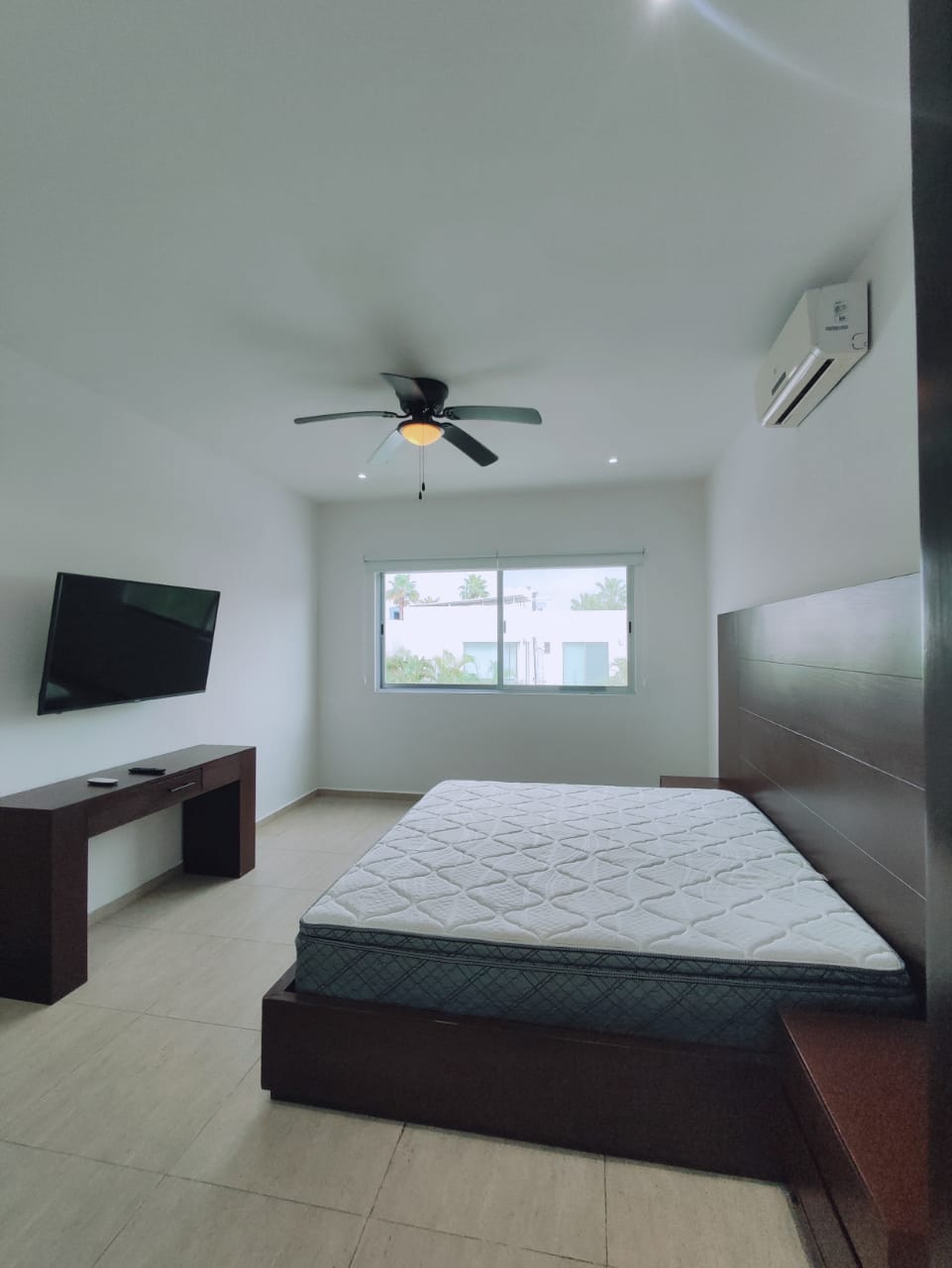 una recamara con una cama king size, un escritorio, una tv en residencial playa magna playa del carmen