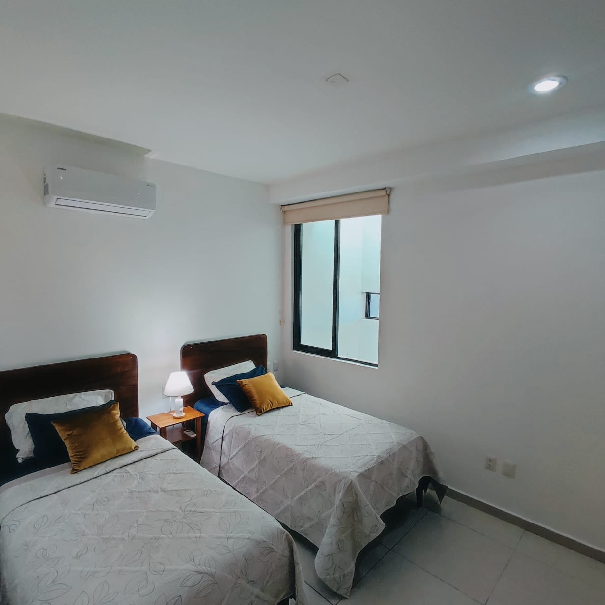 una recamara con 2 camas individuales y un aire acondicionado en playa aurora playa del carmen