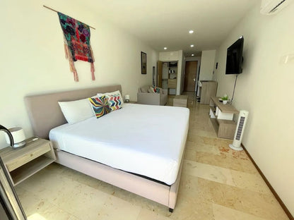 una cama king size, una tv y una barra desayunadora al fondo en a perfect place playa del carmen