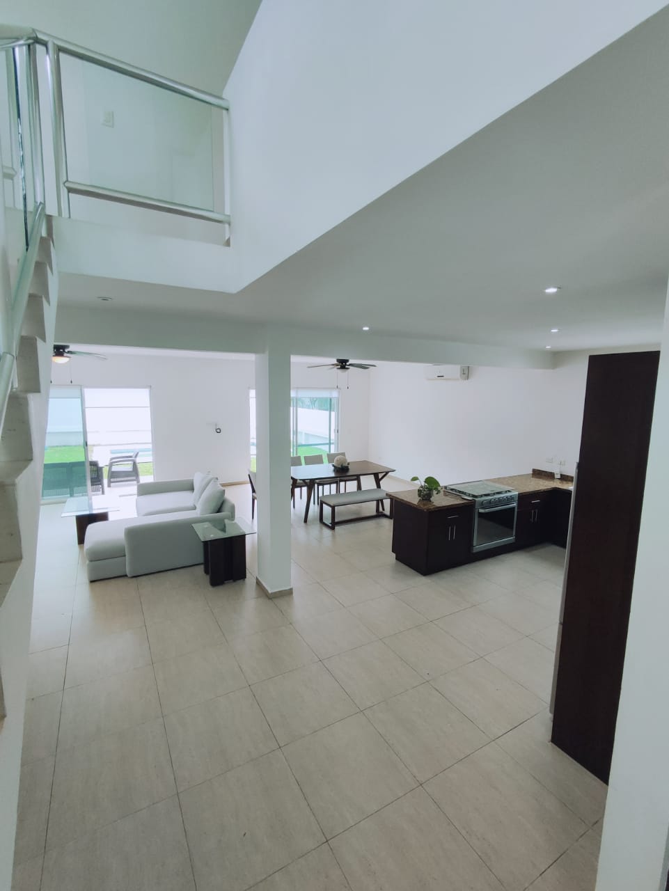 una sala con doble altura con un comedor al fondo en residencial playa magna playa del carmen