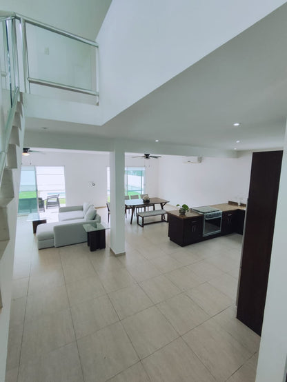 una sala con doble altura con un comedor al fondo en residencial playa magna playa del carmen