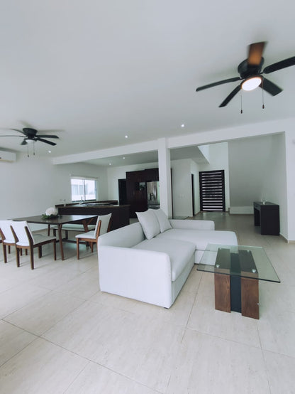 una estancia grande con un comedor y una cocina al fondo en residencial playa magna playa del carmen