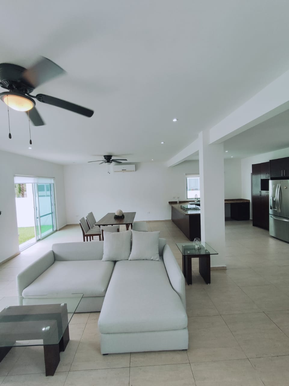 una sala amplia iluminada con un comedor grande y vista al jardin en residencial playa magna playa del carmen