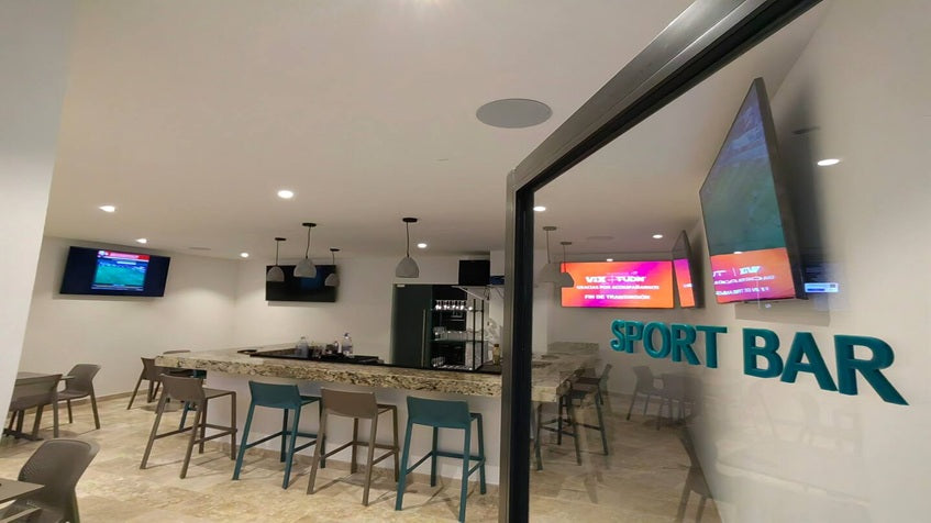 un sport bar con sillas y una tv en ipana condos playa del carmen