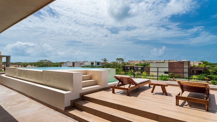 una terraza, dos camastros y una alberca en mak tulum