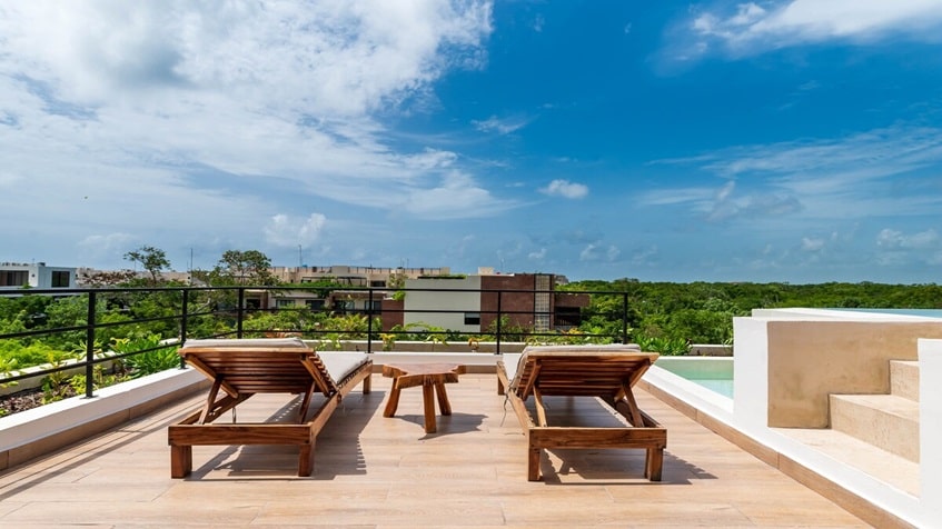 una terraza con 2 camastros y vista al exterior en mak tulum