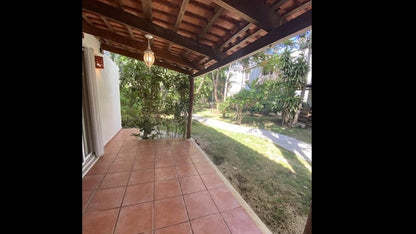 una terraza techada con areas verdes enfrente en villas pakal playacar