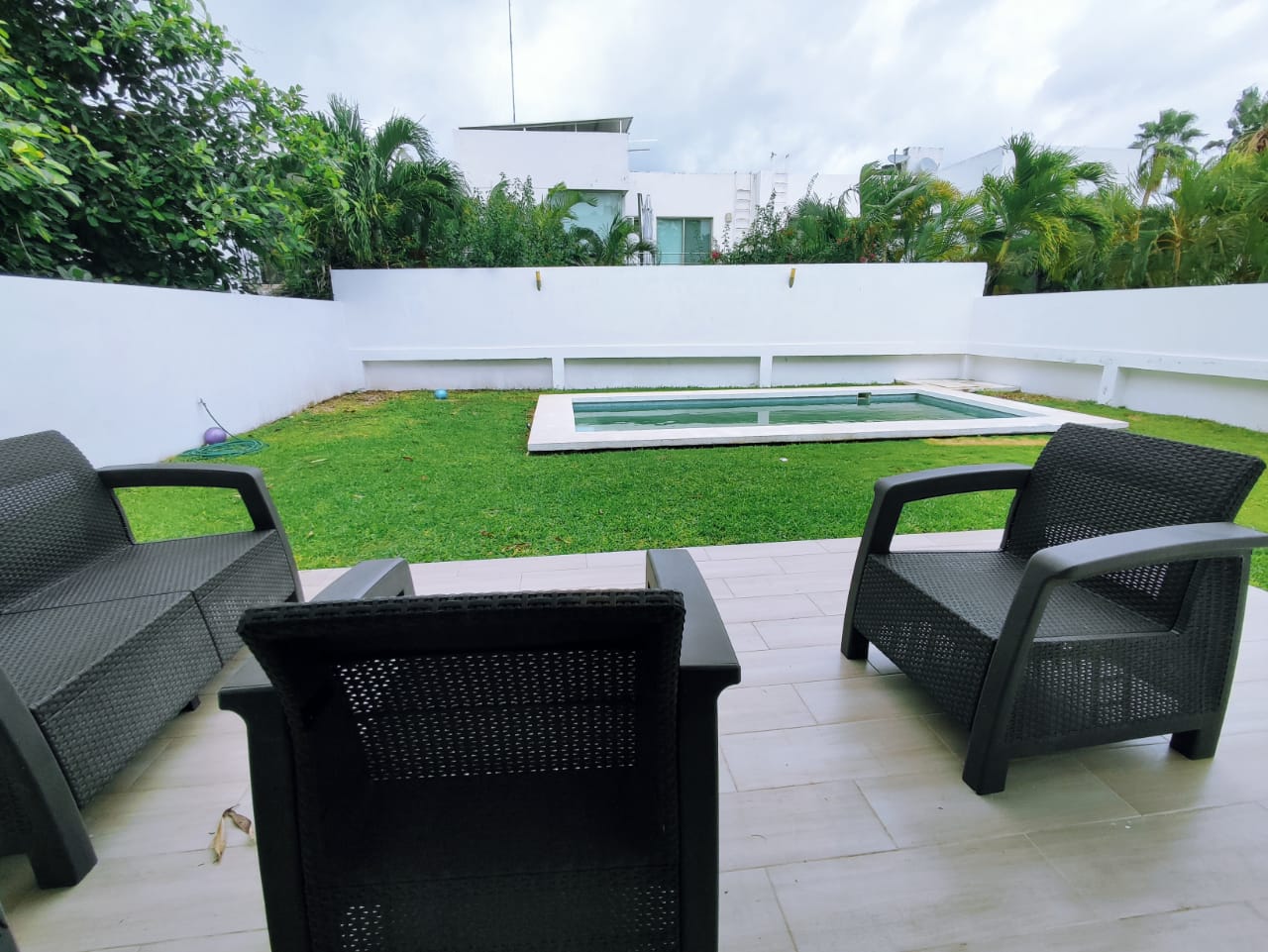 una terraza privada con 3 sillas y vista al jardin en residencial playa magna playa del carmen