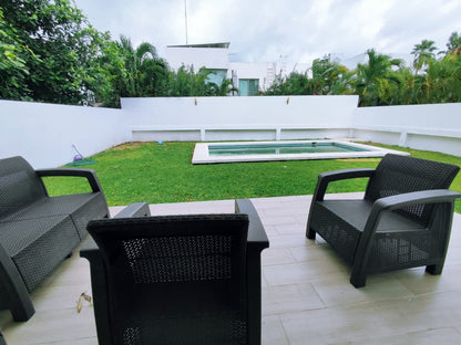 una terraza privada con 3 sillas y vista al jardin en residencial playa magna playa del carmen