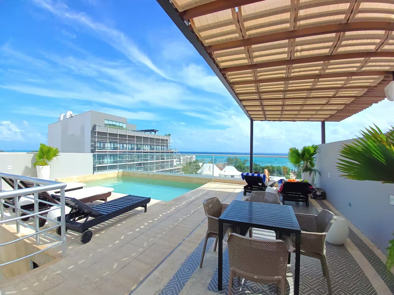 una terraza con una alberca y un area de camastros en menesse on the beach playa del carmen