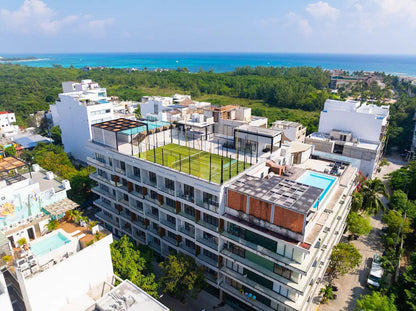 una vista aerea de un edificio con una alberca y una cancha de tenis en macondo 5ta avenida playa del carmen