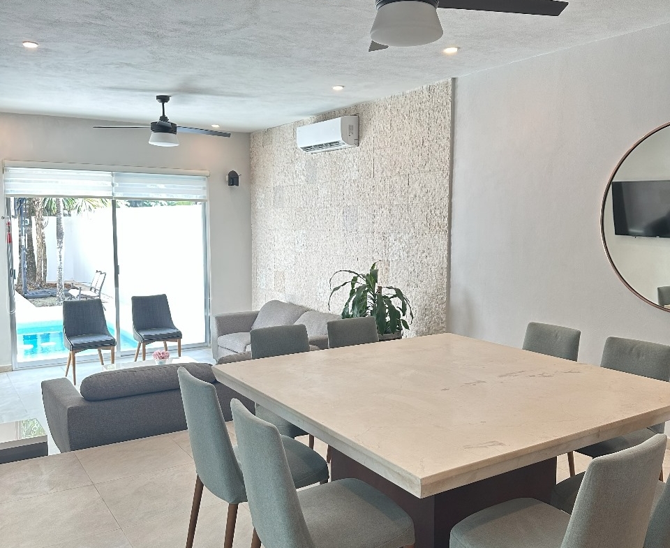 una sala y un comedor con vista a la alberca en playa magna playa del carmen