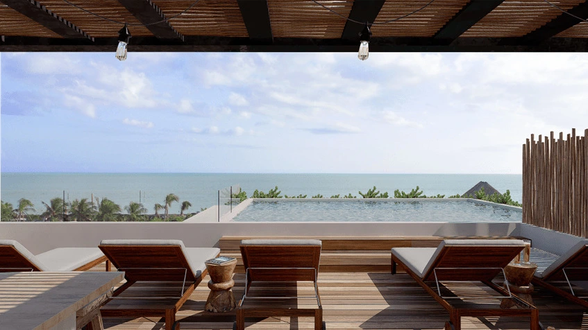 una alberca, unos camastros y una terraza con frente al mar en kaban holbox