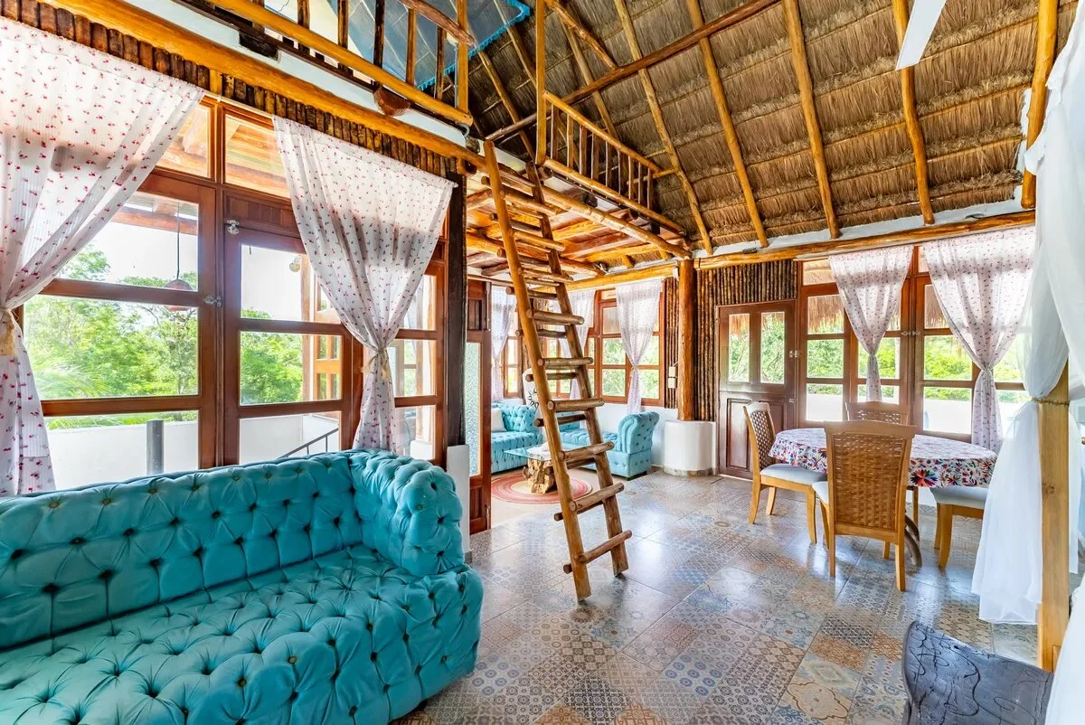 un area de sala, un sofa azul turquesa elegante y una escalera rustica de madera en xcaret playa del carmen