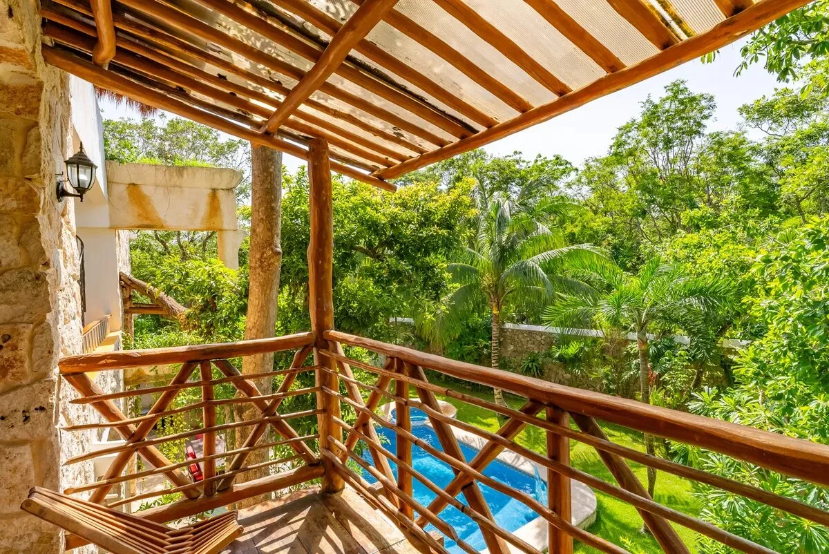 un balcon de madera con vista al jardin y a la sala en xcaret playa del carmen