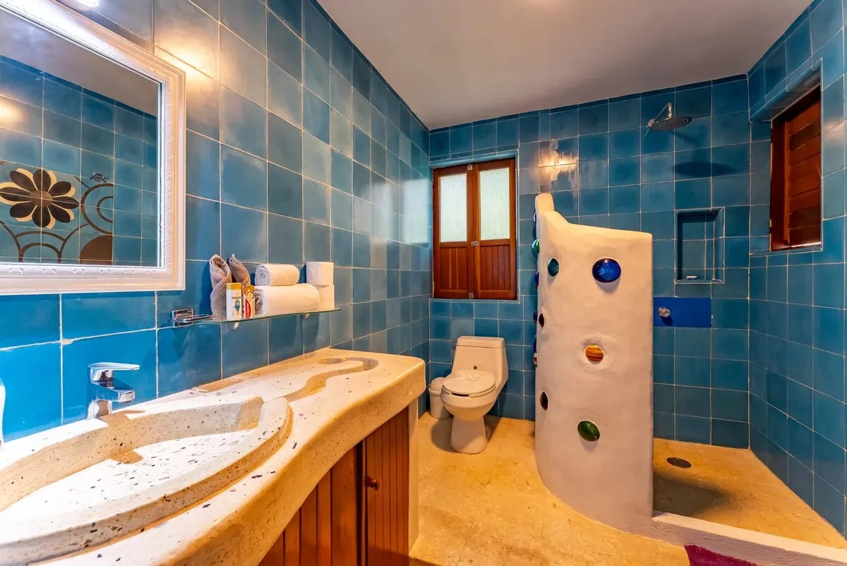 un baño con azulejos azules, un lavamanos y una ducha en xcaret playa del carmen