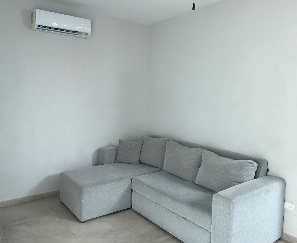 un sofa cama en una sala y un ventilador de techo en playa magna playa del carmen
