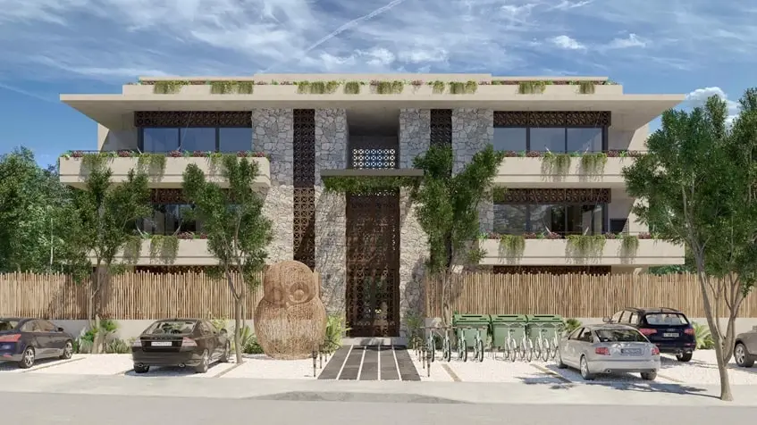 una fachada exterior con departamentos y carros alrededor en muwan tulum