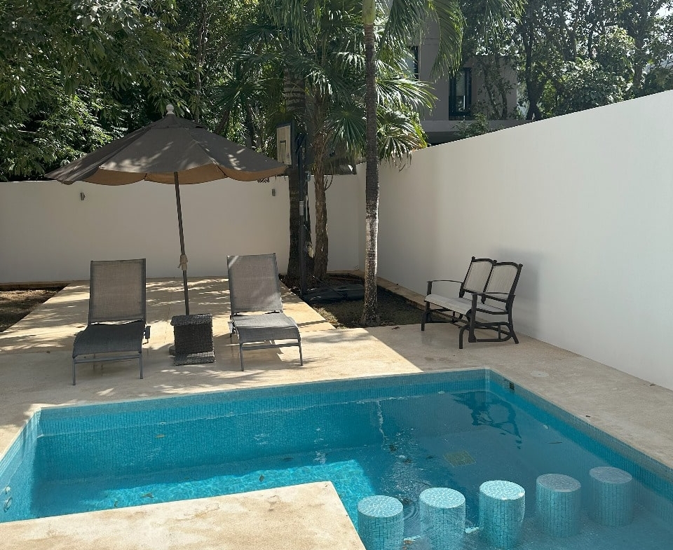 una alberca con camastros y areas verdes en playa magna playa del carmen
